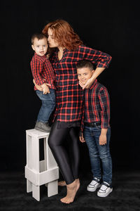 Full length portrait of boy standing against black background