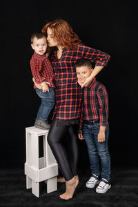 Full length portrait of boy standing against black background