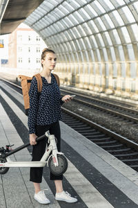 Young woman with electric scooter at the train station