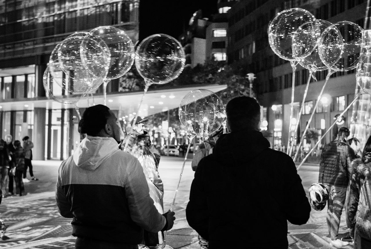 group of people, night, women, real people, architecture, men, adult, illuminated, rear view, city, leisure activity, built structure, arts culture and entertainment, lifestyles, people, standing, crowd, decoration, disco ball, nightlife