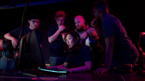 Woman using computer by friends in darkroom