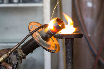 Cropped hand burning metal at workshop