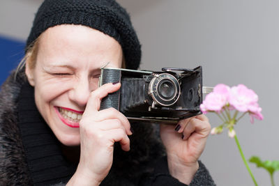 Smiling mature woman photographing with vintage camera