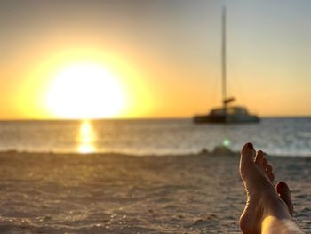 Low section of person on beach at sunset