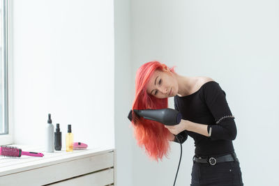 Portrait of young woman standing against wall at home