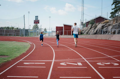 Father running with his kids on a race track