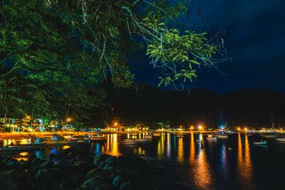 Illuminated city by river at night