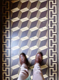 Low section of man standing on tiled floor