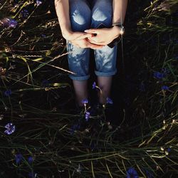 Low section of woman sitting on grassy field