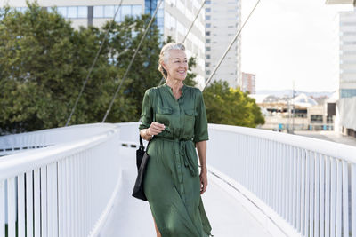 Smiling mature woman walking on footbridge