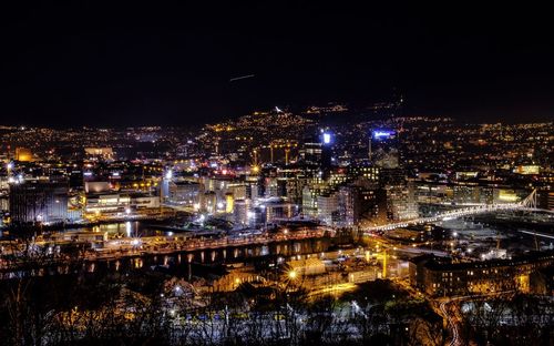 Illuminated cityscape against sky at night