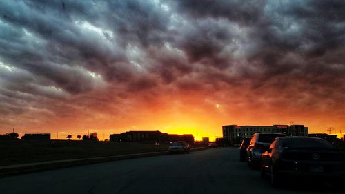 Cars on road against dramatic sky during sunset