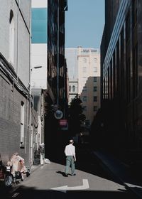 Rear view of people walking on street amidst buildings