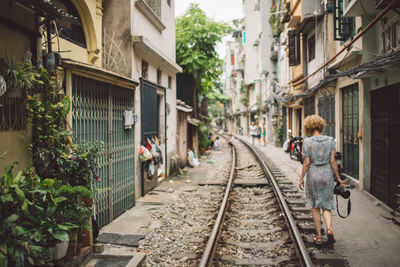 Woman walking on railroad track in city