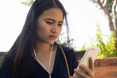 Beautiful young woman using mobile phone outdoors