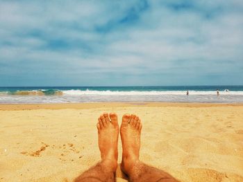 Low section of man sitting at beach