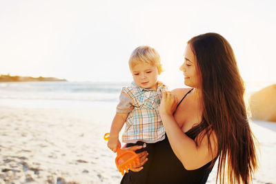 Mother and son at beach against sky