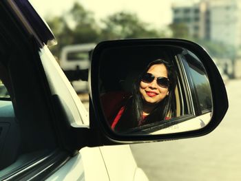 Portrait of a smiling young woman on side-view mirror