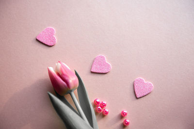 Close-up of pink tulips by heart shape sweet food and beads on table