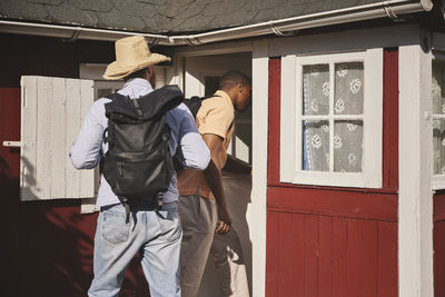 Young men entering wooden house