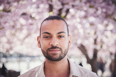 Portrait of young man standing under cherry blossom