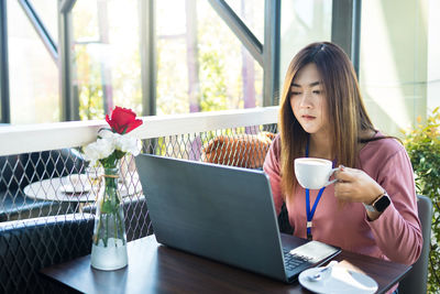 Young woman using laptop on table at home