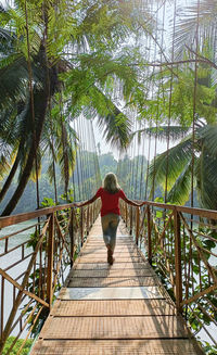 Rear view of woman walking on footbridge