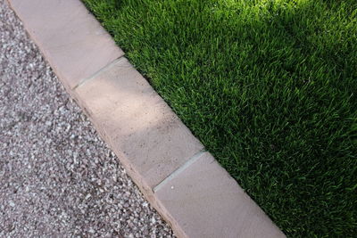 High angle view of gravel footpath by grass