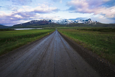 Road amidst field against sky during winter