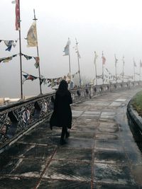 Rear view of woman walking on road against sky