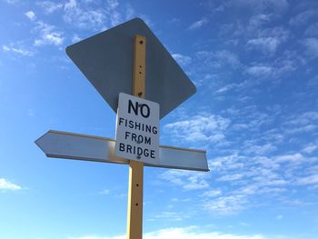 Low angle view of road sign against blue sky