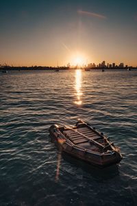 Boat moored on shore against sky during sunset