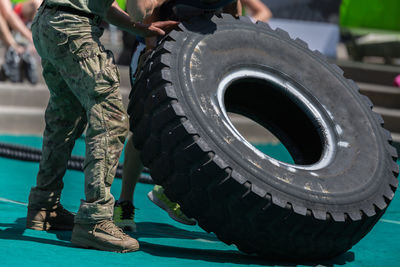 Low section of men carrying tire