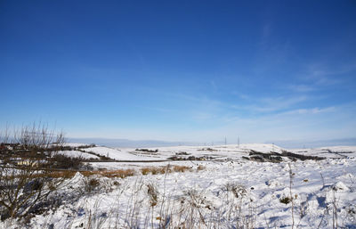 Snow covered landscape against blue sky