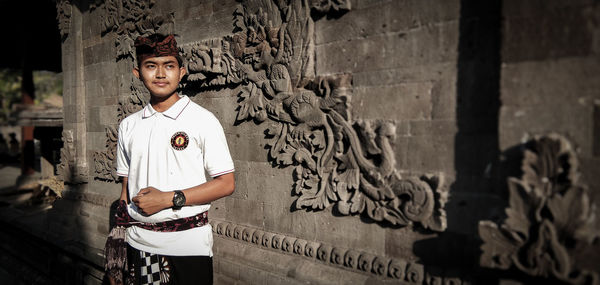 Portrait of young woman standing against wall