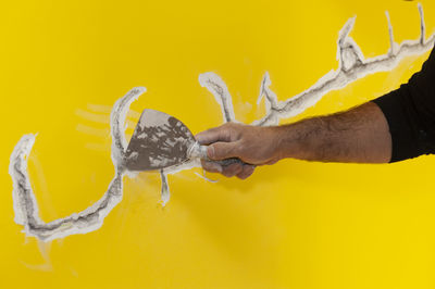 Cropped hand of man scraping wall with tool