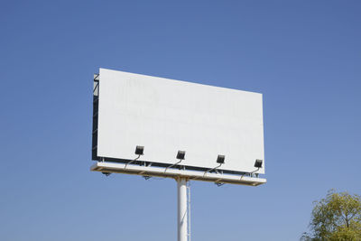 Low angle view of telephone booth against clear blue sky