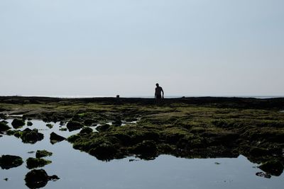 Men standing on field against sky