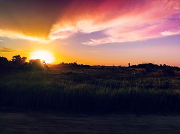 Scenic view of silhouette field against sky during sunset