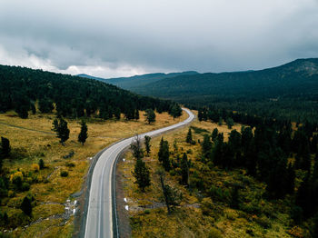 Road amidst trees and mountains against sky