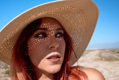 Close-up of a young woman with red hair and a hat. concept looks