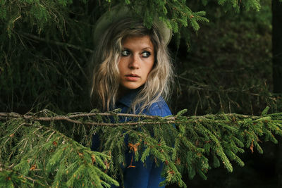 The girl in the blue dress behind the branches of the fir