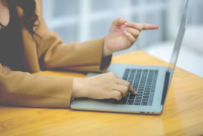 Midsection of man using mobile phone while sitting on table