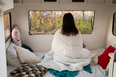 Rear view of women sitting on bed