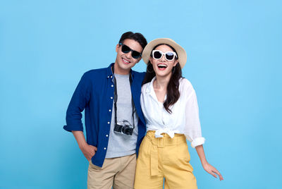 Young couple wearing sunglasses standing against blue sky