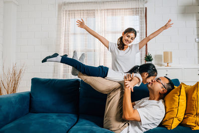 Side view of friends exercising on sofa at home