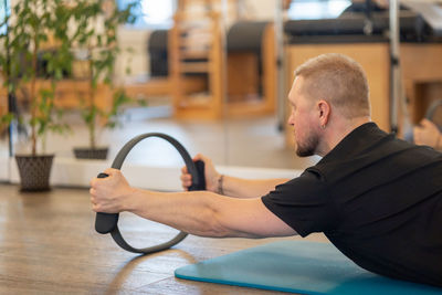 Male fitness pilates trainer shows exercises on special simulators. rubber rings for stretching