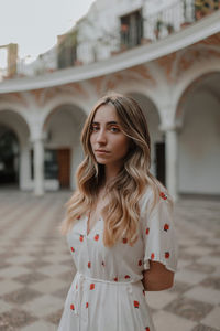 Portrait of beautiful young woman standing against built structure