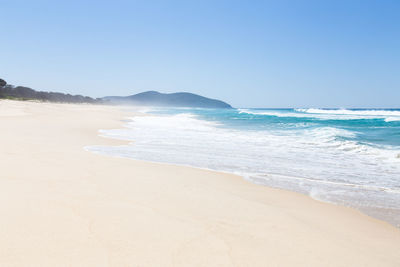 Scenic view of beach against clear blue sky