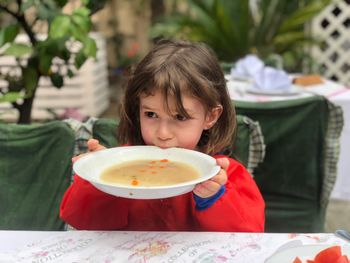 Girl drinking soup at table
